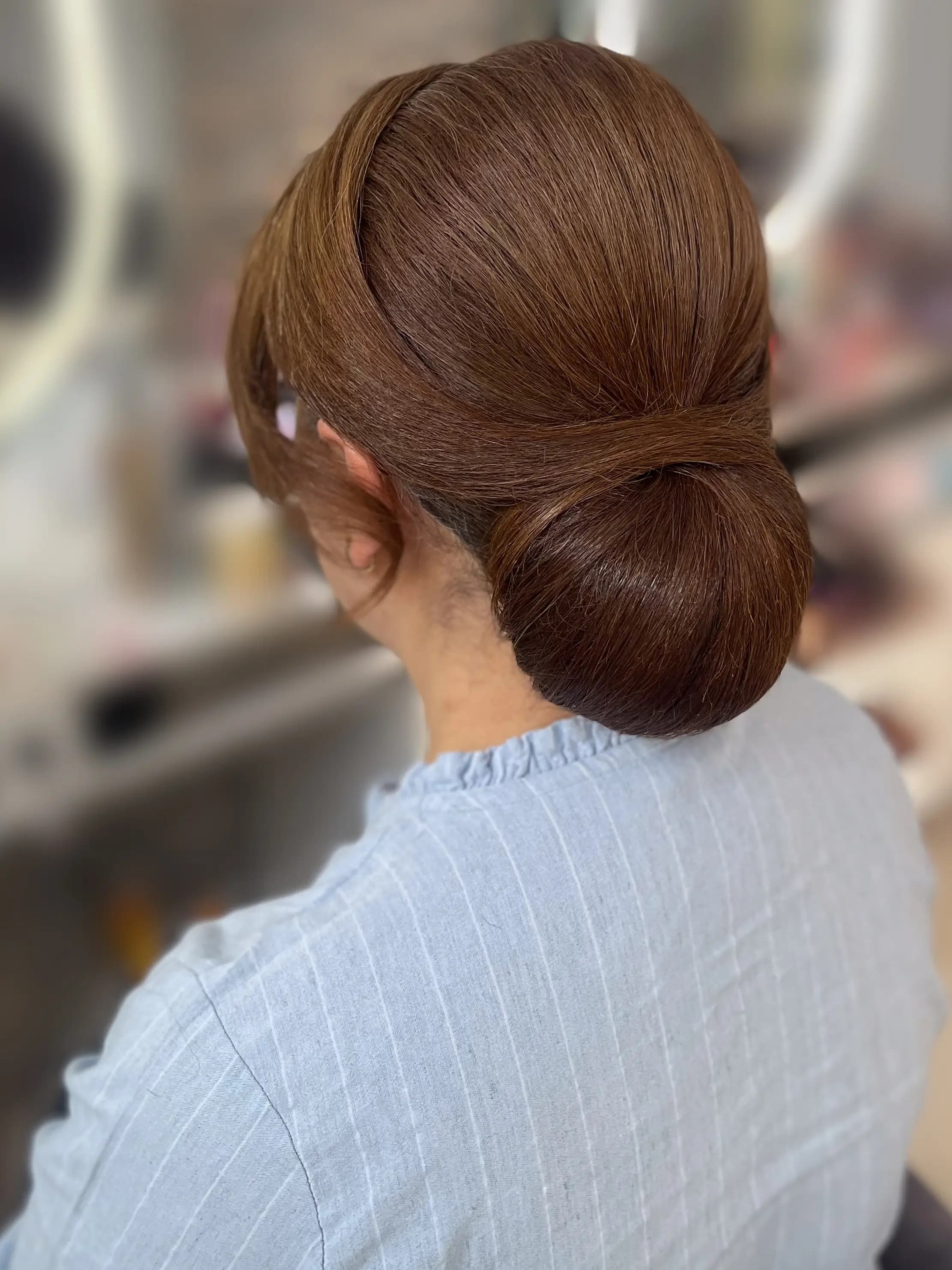 Elegante Hochsteckfrisur mit glattem Chignon und seitlich locker fallenden Strähnen, Rückansicht, Brautstyling Hamburg